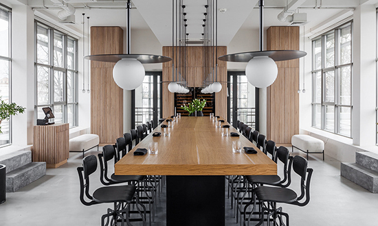 Stylish meeting room with glass walls, modern wooden conference table and black chairs around in light interior design office with stylish lamps